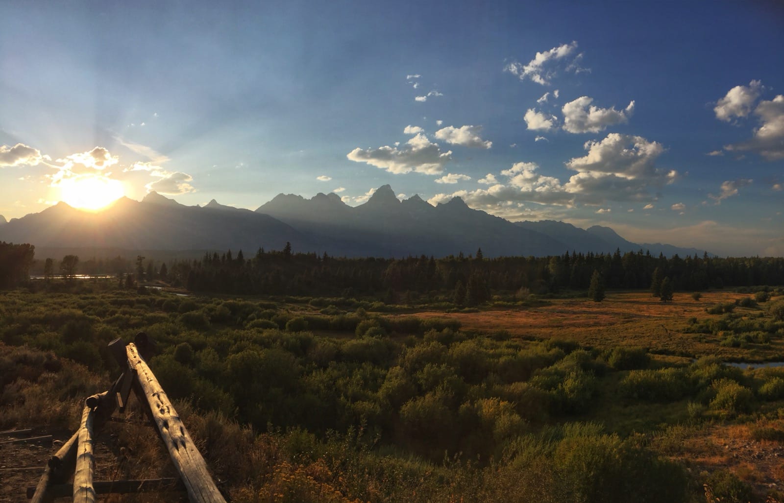 Color photo of a sunset going behind the Teton mountains.